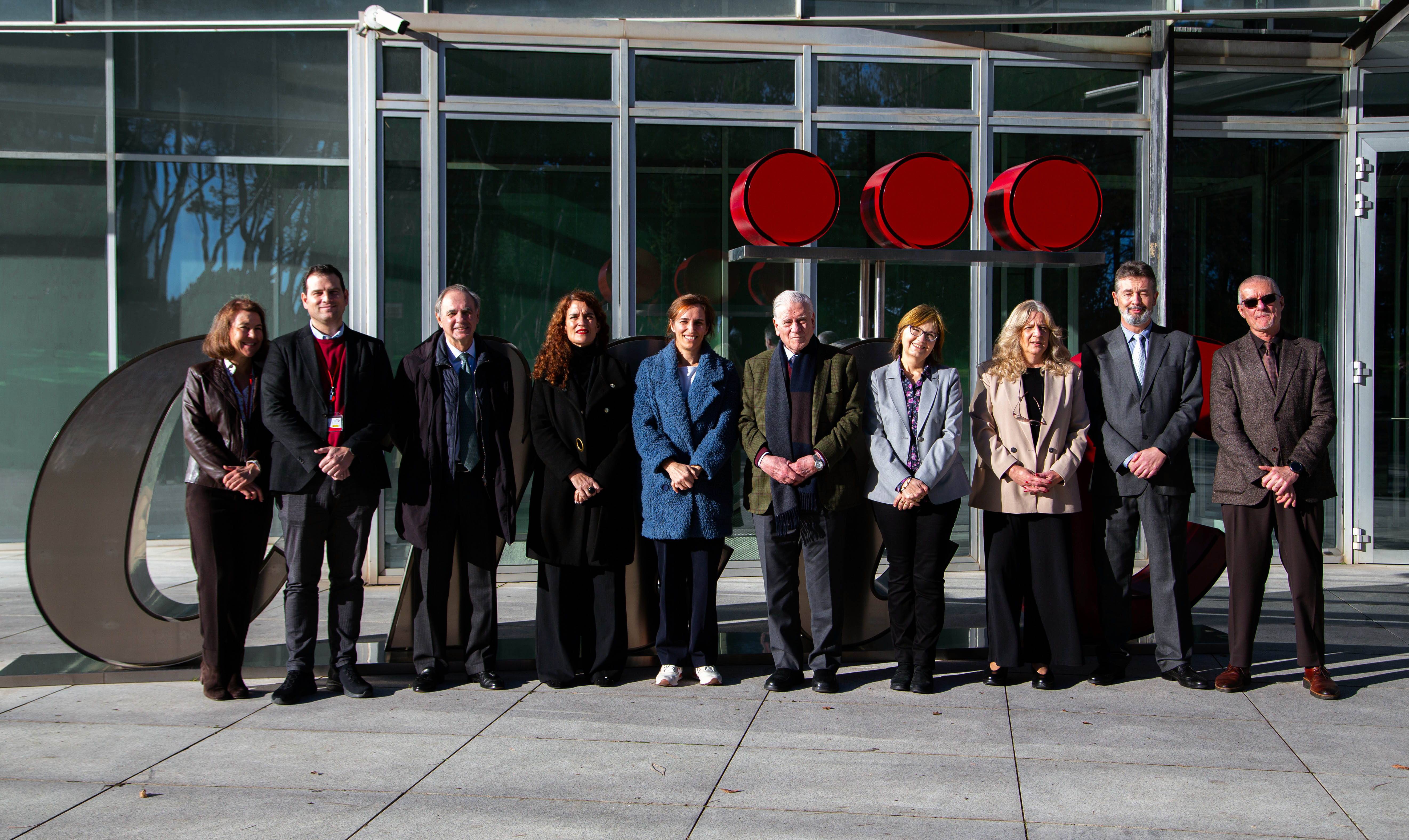 Foto de familia de la visita de ministra de Sanidad al CNIC, en la puerta principal del centro, situado en el Campus de Chamartín del ISCIII, en Madrid. En el centro, la ministra Mónica García, con la secretaria general de Investigación del Ministerio de Ciencia, Innovación y Universidades, Eva Ortega Paíno; la directora del ISCIII, Marina Pollán, la subdirectora Marta Ortiz, y el director del CNIC, el doctor Valentín Fuster, acompañados de parte del personal directivo y científico del centro. 